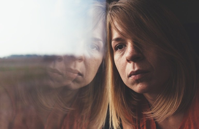 Mujer junto a una ventana en una imagen sobre violencia de género