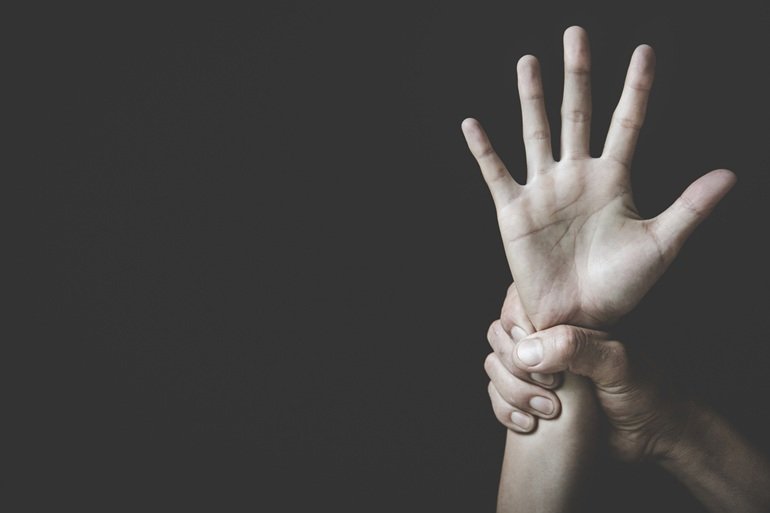Mano sujetando la muñeca de una mujer como representación de la violencia y el control